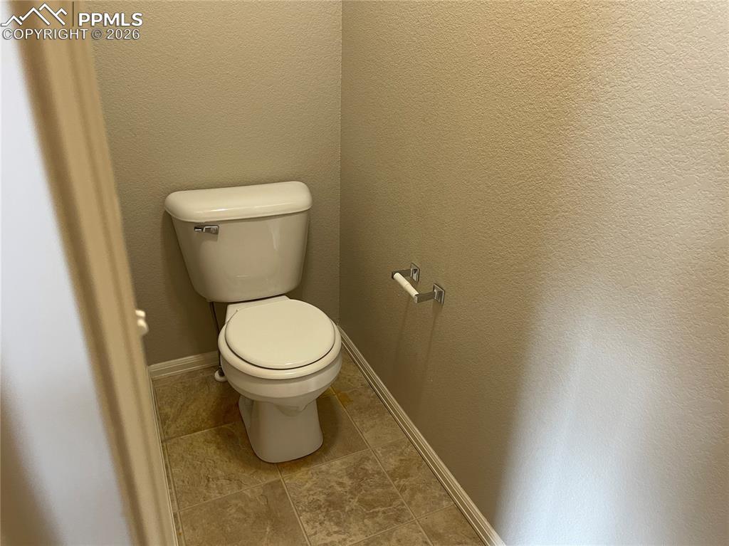 Image 12 of 15: White toilet with chrome flush handle and a coordinating wall-mounted toile