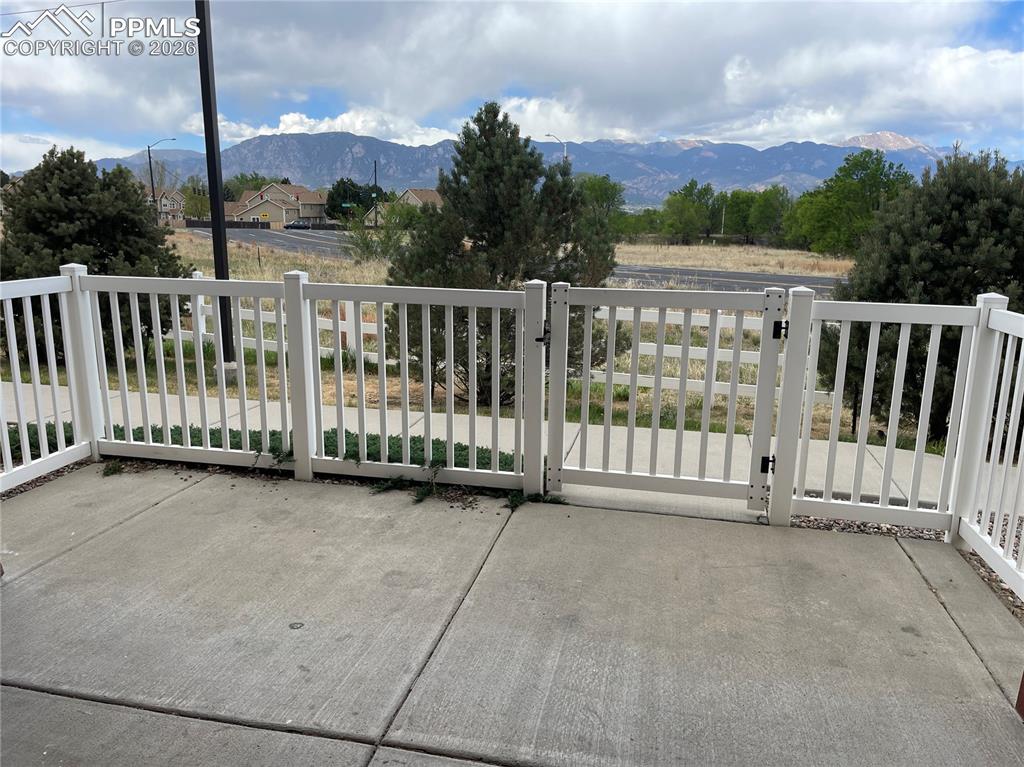 Image 15 of 15: Concrete patio featuring a white slatted fence and gate