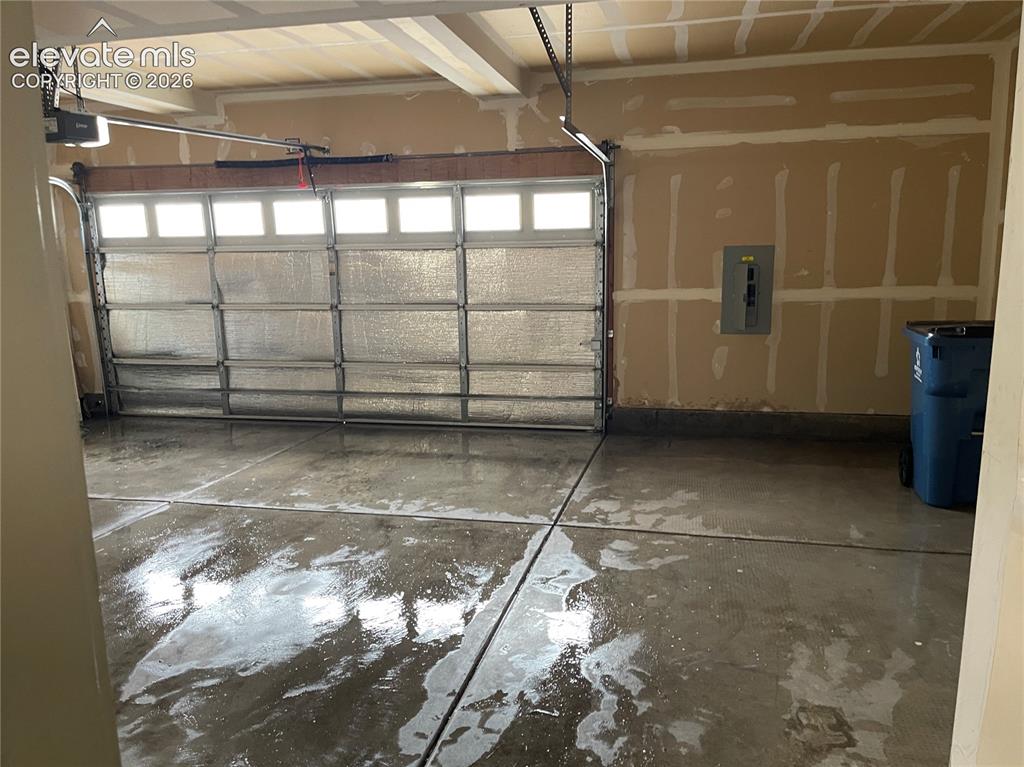 Image 17 of 18: Spacious garage featuring a concrete floor, an overhead garage door with wi