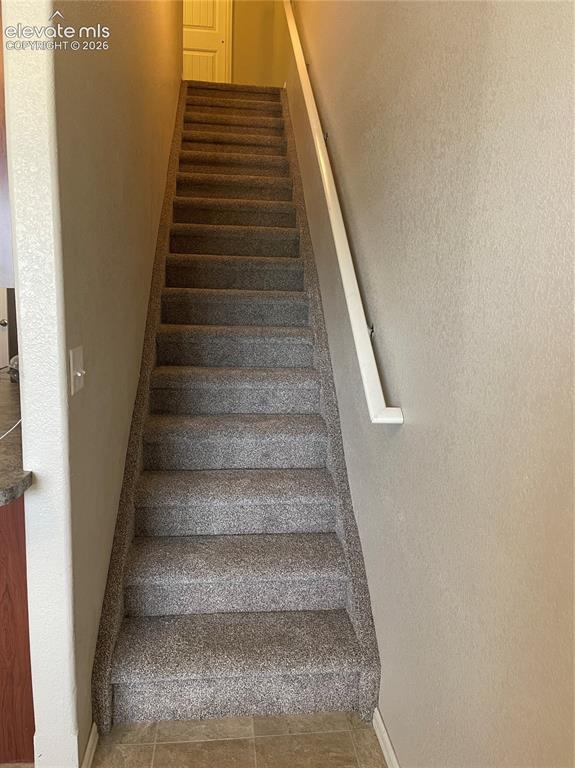 Image 18 of 18: Staircase with gray carpeted steps and a white handrail