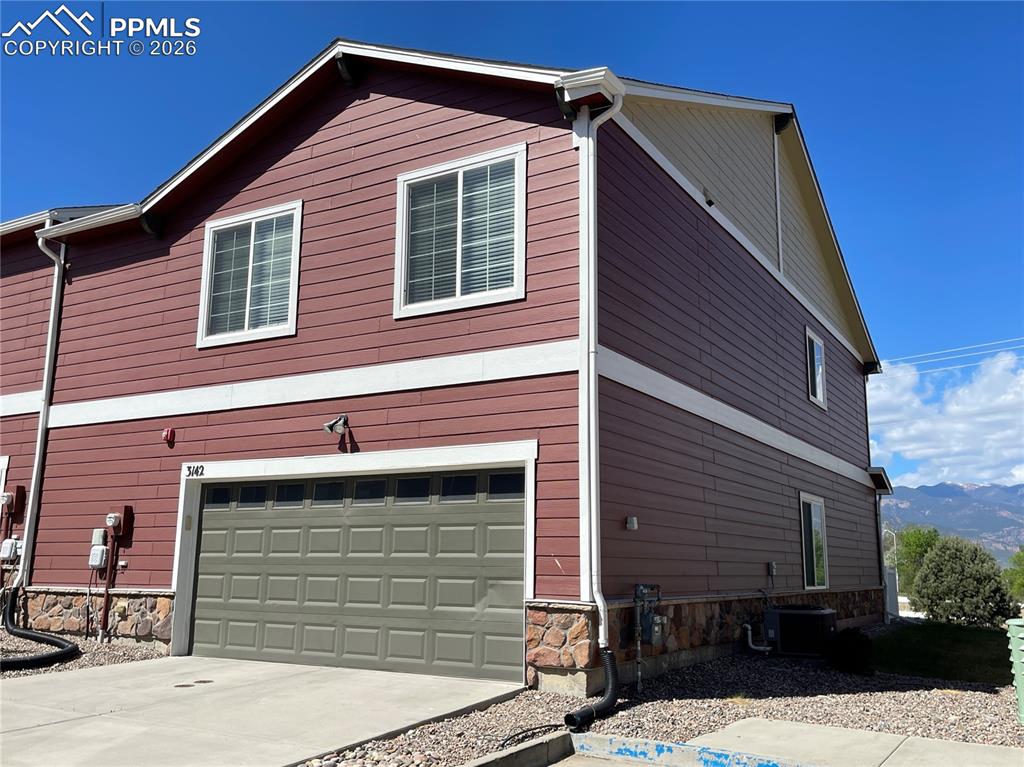Image 2 of 15: Multi-story exterior with horizontal siding in two tones, an integrated gar