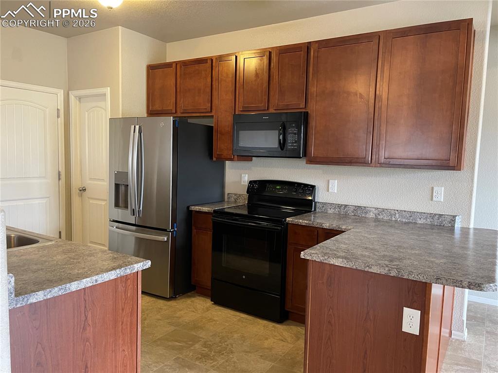 Image 4 of 15: Functional kitchen featuring wood-finish cabinetry, stainless steel refrige