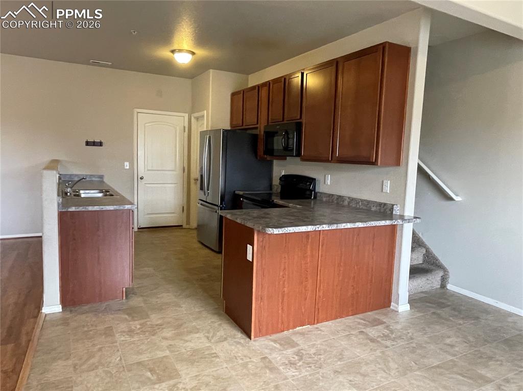 Image 5 of 15: Kitchen featuring wood-finish cabinetry and gray speckled countertops