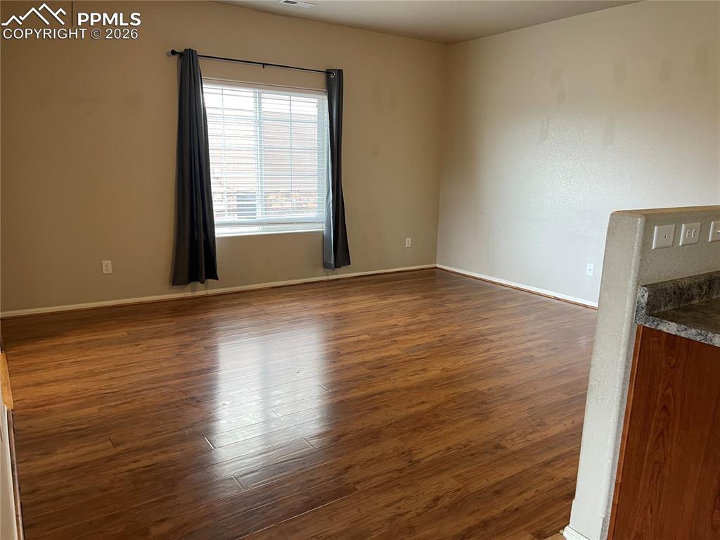 Image 6 of 15: Spacious room featuring wood-finish flooring, neutral-toned walls, and a la