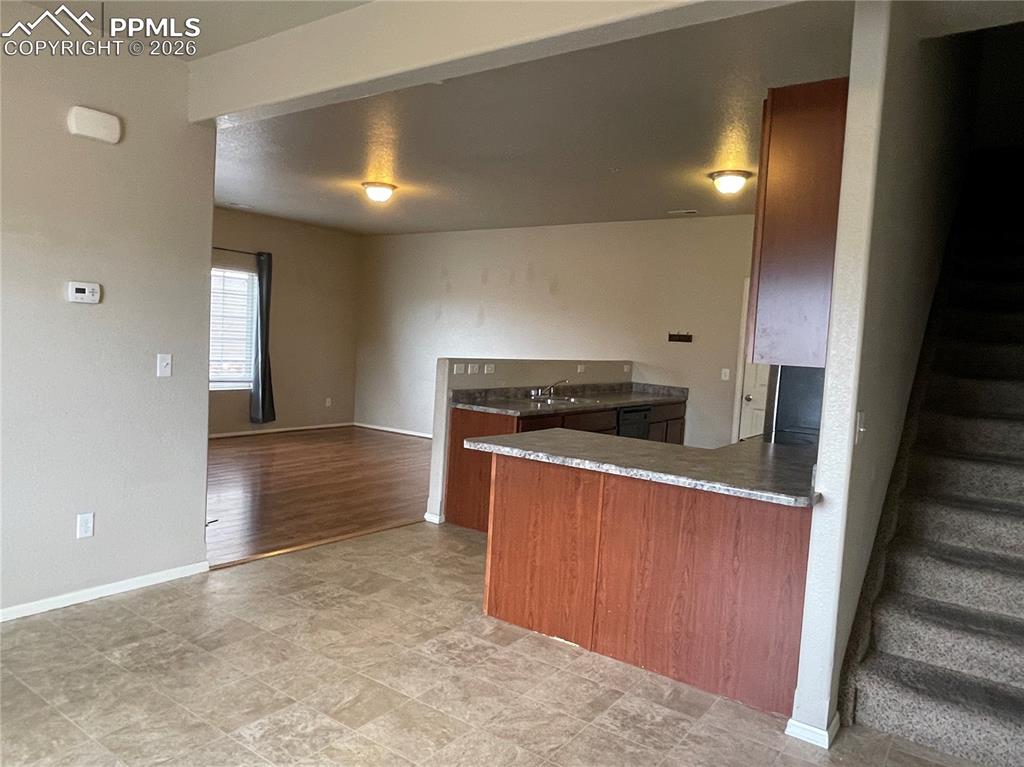 Image 7 of 15: Kitchen bar seating area with wood-finish cabinetry and a speckled countert