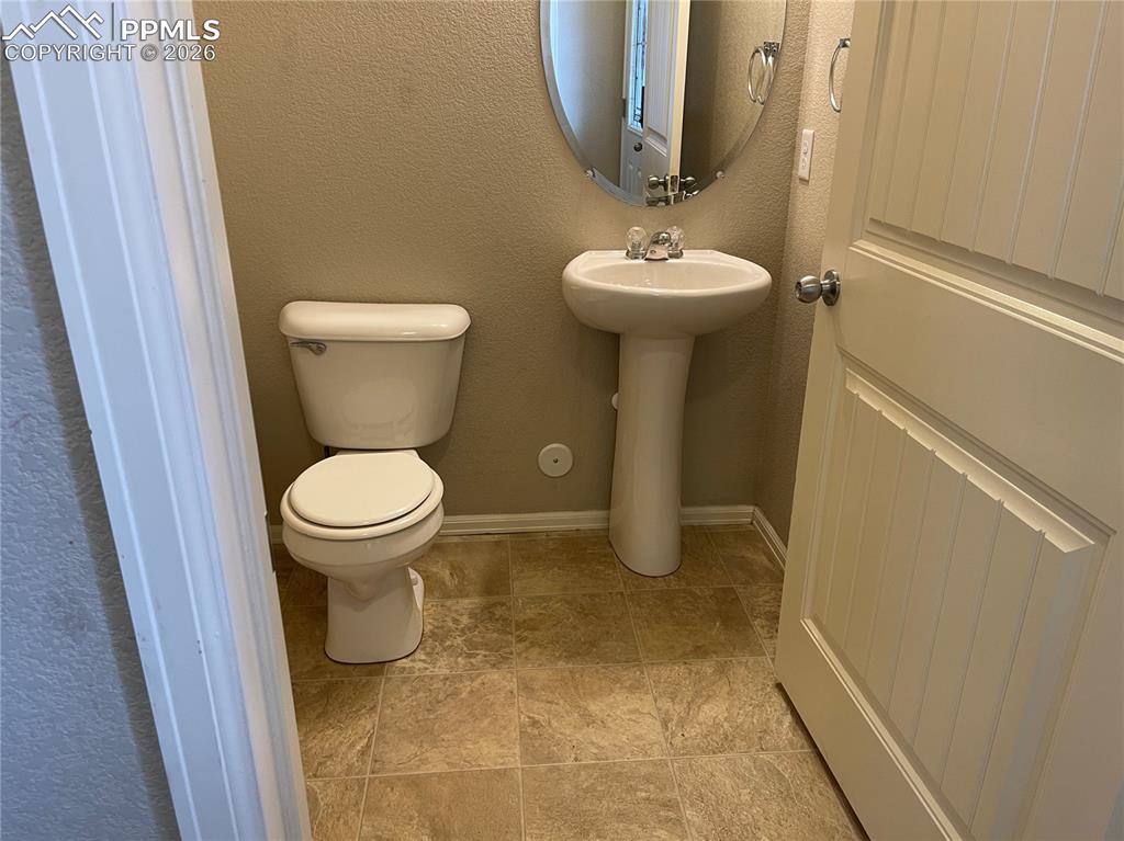 Image 8 of 15: Powder room featuring a pedestal sink with a chrome faucet, oval mirror, an