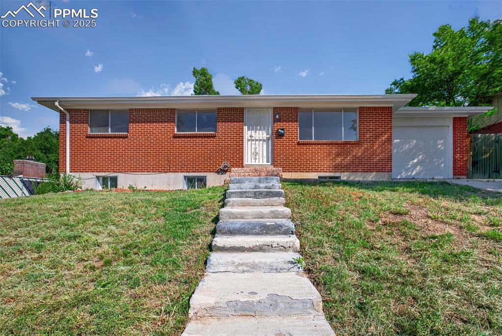 Caption: Single story home with a front lawn, an attached garage, and brick siding