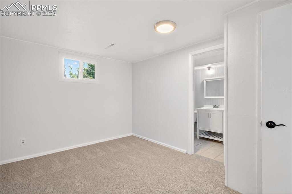 Image 15 of 17: Unfurnished bedroom with light colored carpet and connected bathroom