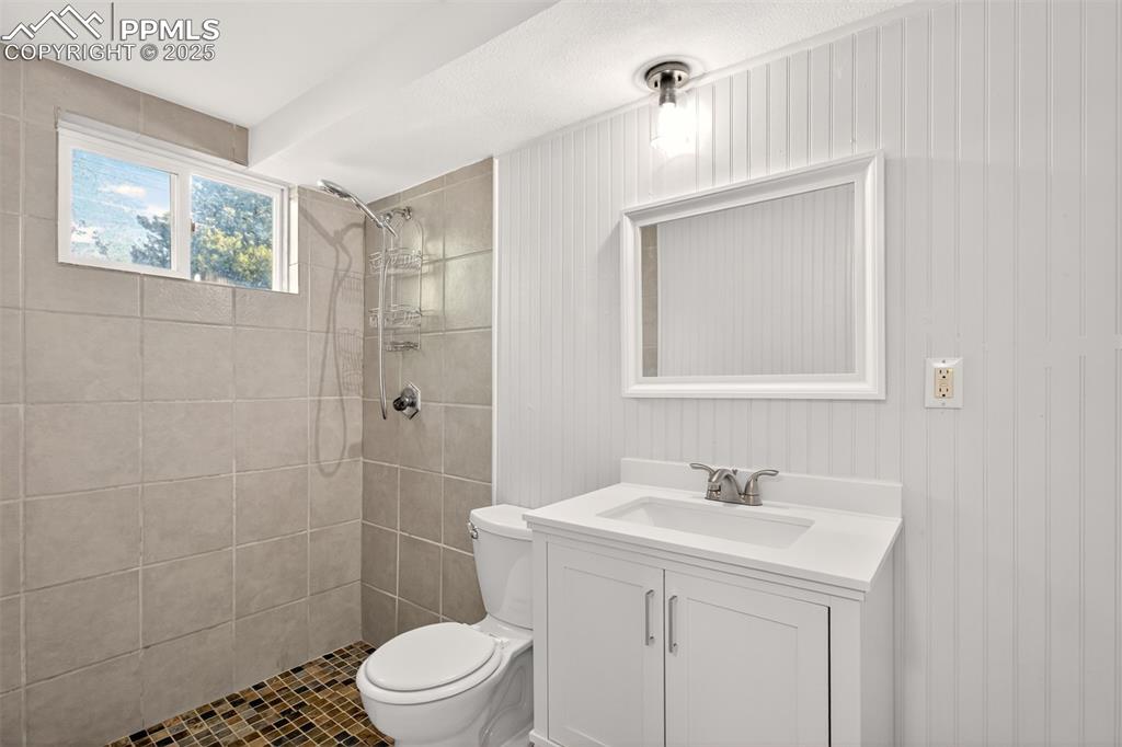 Image 16 of 17: Bathroom featuring a tile shower, vanity, and tile patterned flooring