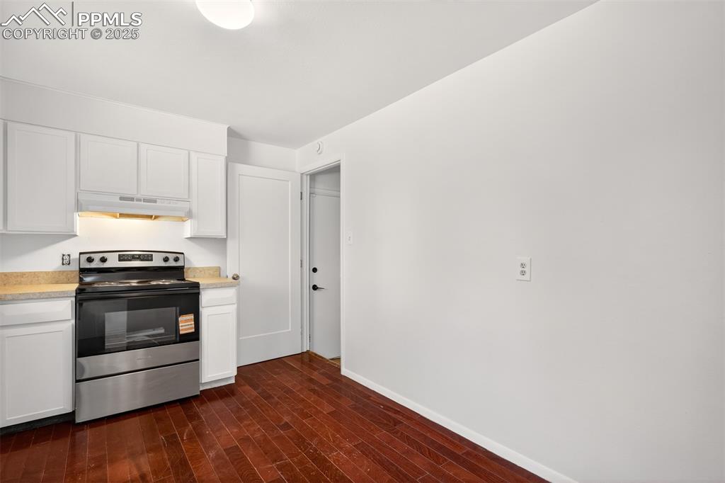 Image 4 of 17: Kitchen with stainless steel electric range, under cabinet range hood, dark