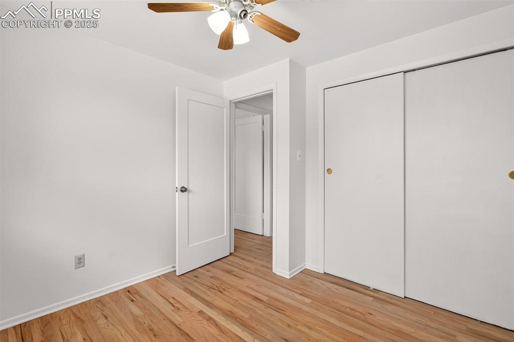 Image 7 of 17: Front bedroom with light wood-style flooring, a closet, and a ceiling fan