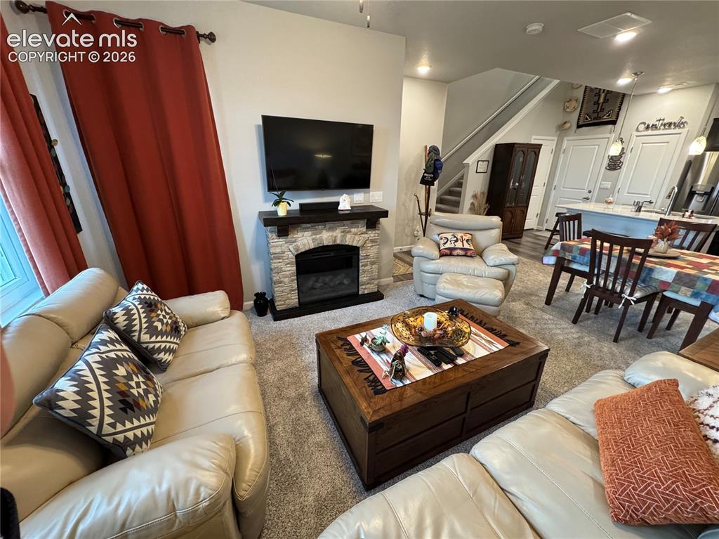 Image 12 of 25: Fireplace featuring a stone-style facade and a dark wood mantel, neutral wa