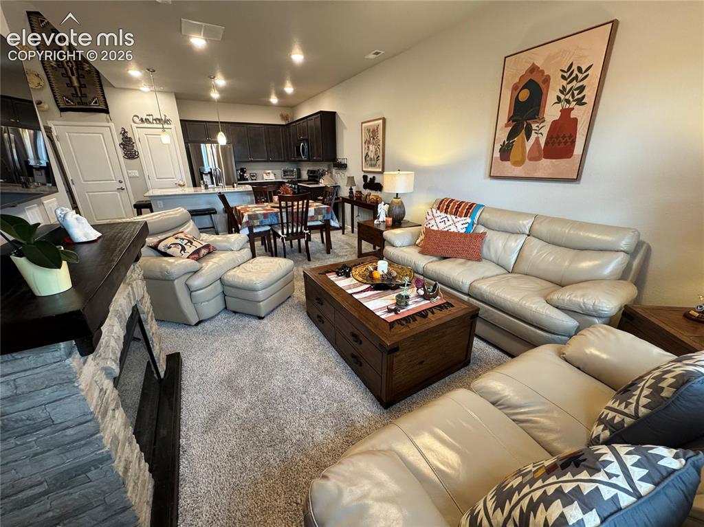 Image 13 of 25: Open-concept area featuring a floor-to-ceiling stone-veneer fireplace, kitc