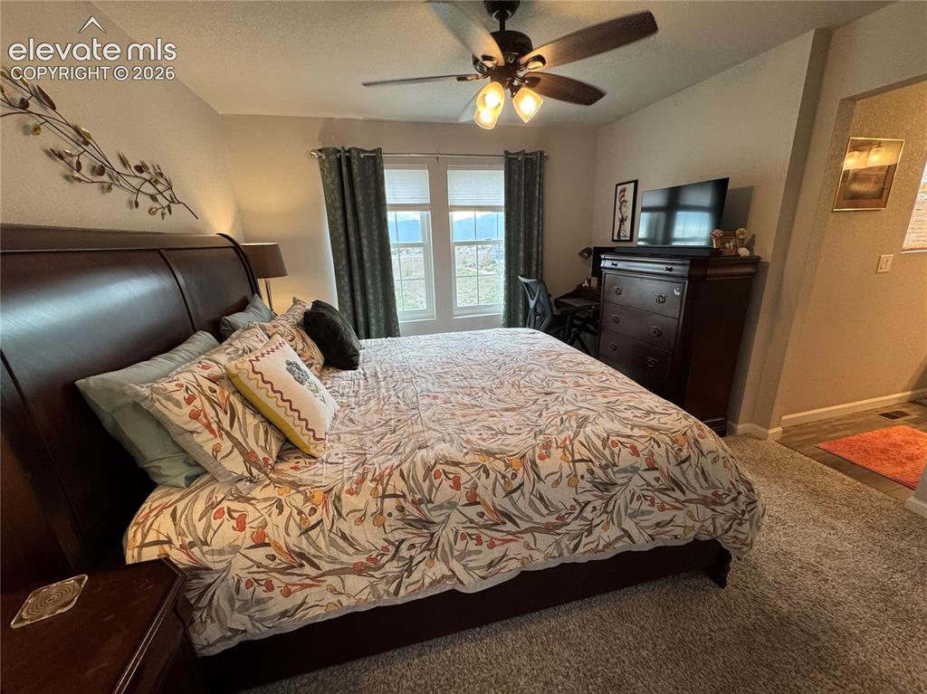 Image 14 of 25: Bedroom featuring neutral carpeting, dual windows, and a ceiling fan with i