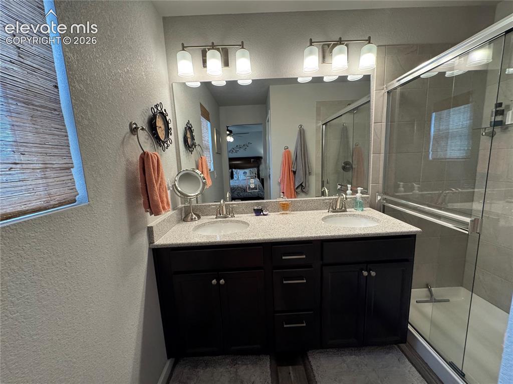 Image 15 of 25: Double vanity featuring dark wood-finish cabinetry, a light-toned solid sur