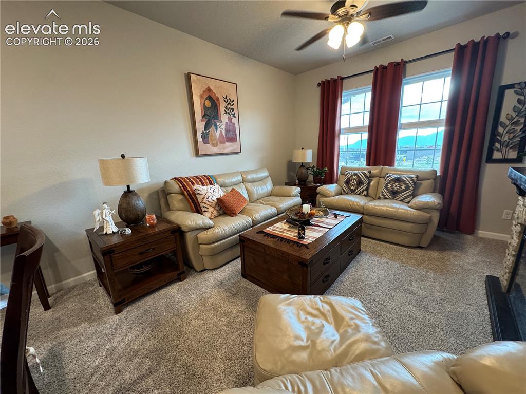 Image 20 of 25: Living space featuring neutral carpeting, a ceiling fan, and large windows 