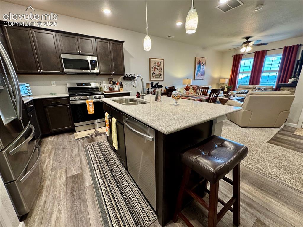 Image 4 of 25: Kitchen featuring dark cabinetry, stainless steel appliances, a central isl
