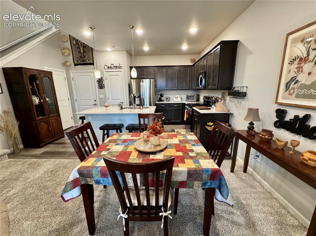 Image 5 of 25: Kitchen featuring dark cabinetry, stone-surfaced island with integrated sin