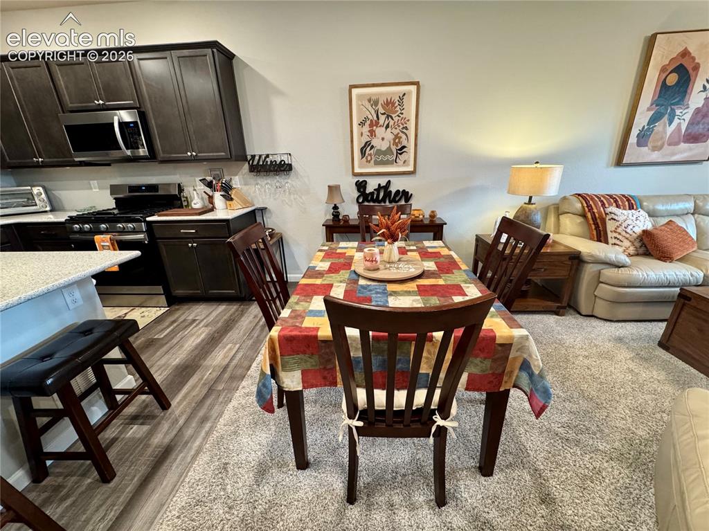 Image 6 of 25: Kitchen featuring dark cabinetry, stone-surface countertops, and wood-finis