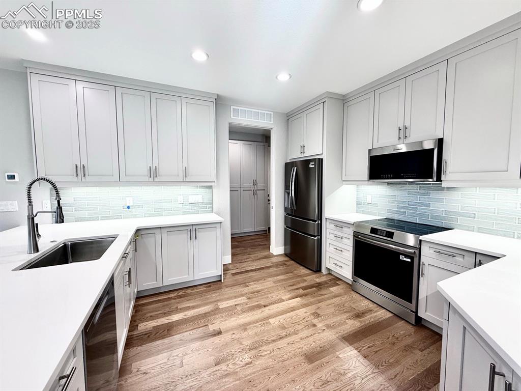 Image 10 of 28: Kitchen with black appliances, light wood-style floors, recessed lighting,