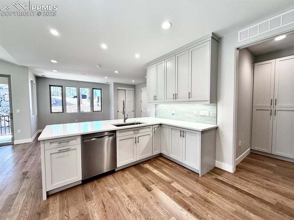 Image 11 of 28: Kitchen featuring dishwasher, a peninsula, recessed lighting, light wood-st