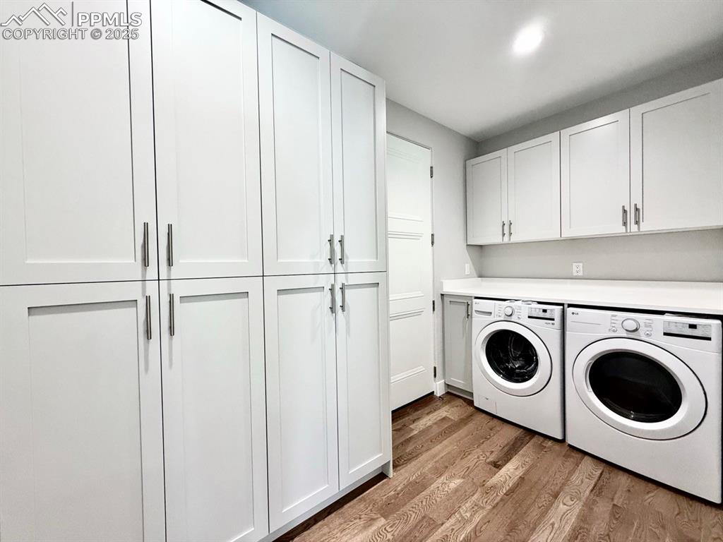Image 13 of 28: Washroom with light wood-type flooring, independent washer and dryer, and c