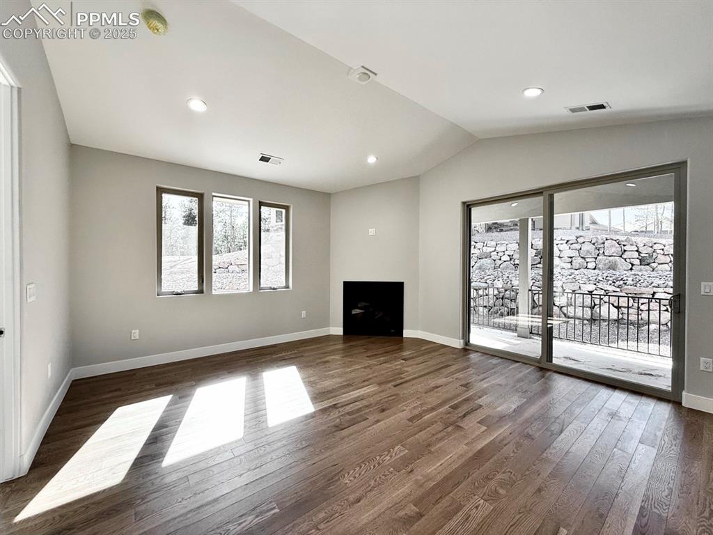 Image 15 of 29: Vaulted Living Room with Gas Fireplace and Sliding Door to Covered Patio.