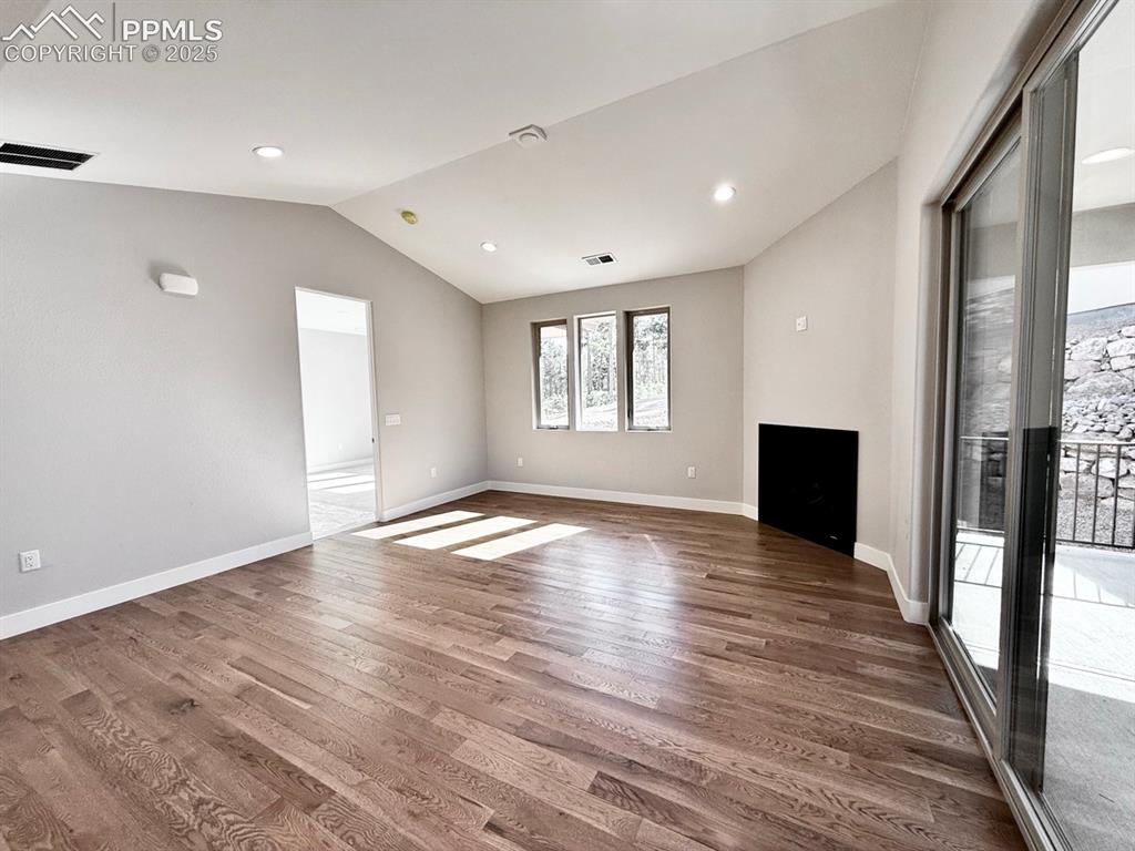 Image 16 of 29: Vaulted Living Room with Gas Fireplace and Sliding Door to Covered Patio.