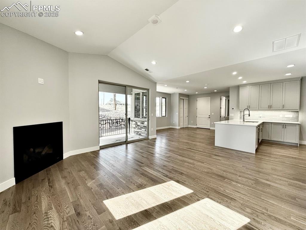 Image 17 of 28: Unfurnished living room with a fireplace, recessed lighting, lofted ceiling