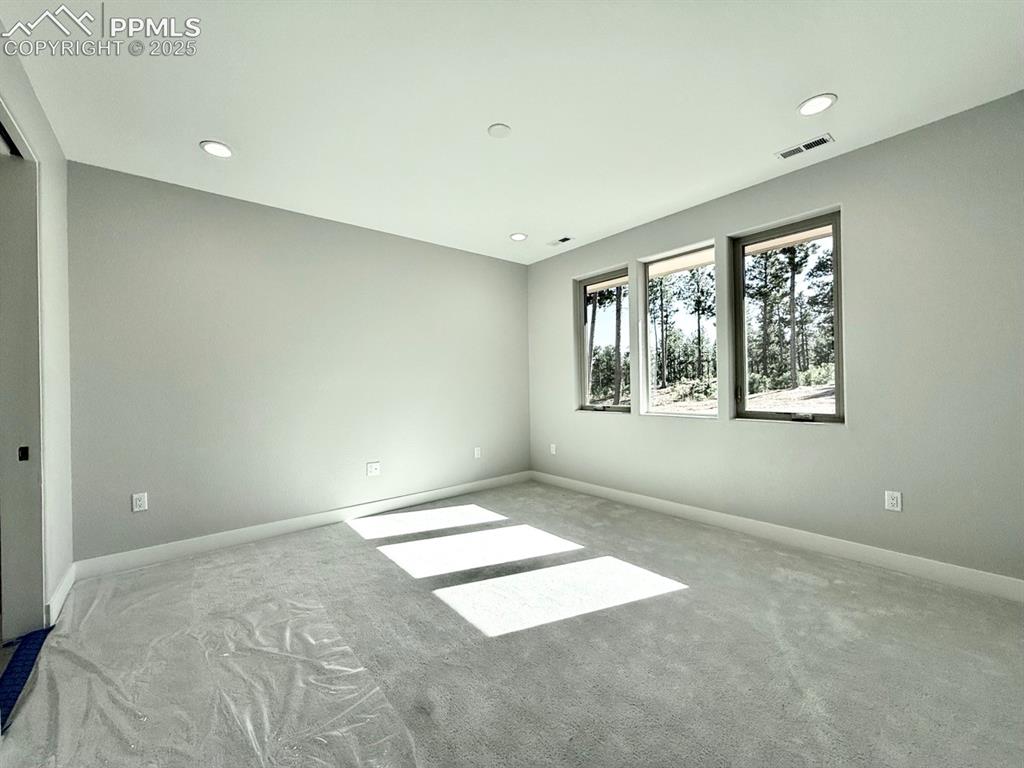 Image 17 of 29: Main Level Primary Suite with Large Windows looking into the Forest and Car