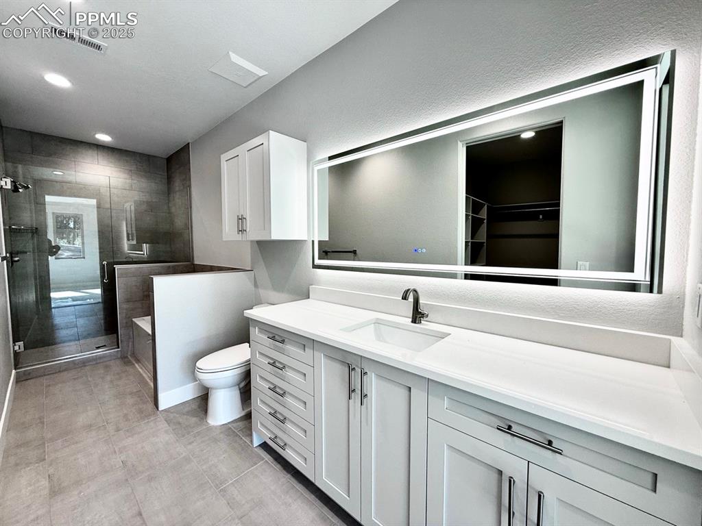 Image 21 of 28: Full bathroom with vanity, a stall shower, a walk in closet, recessed light