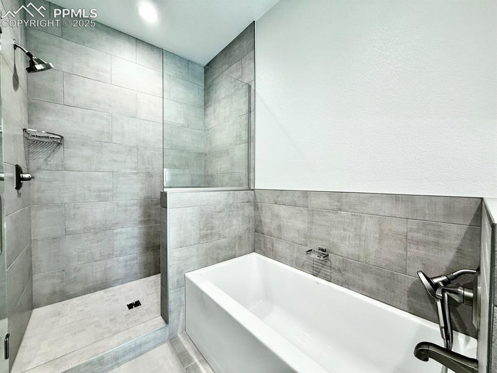 Image 22 of 29: Luxurious Primary Bathroom with Quartz Countertop, Deep Soaking Tub, Tiled