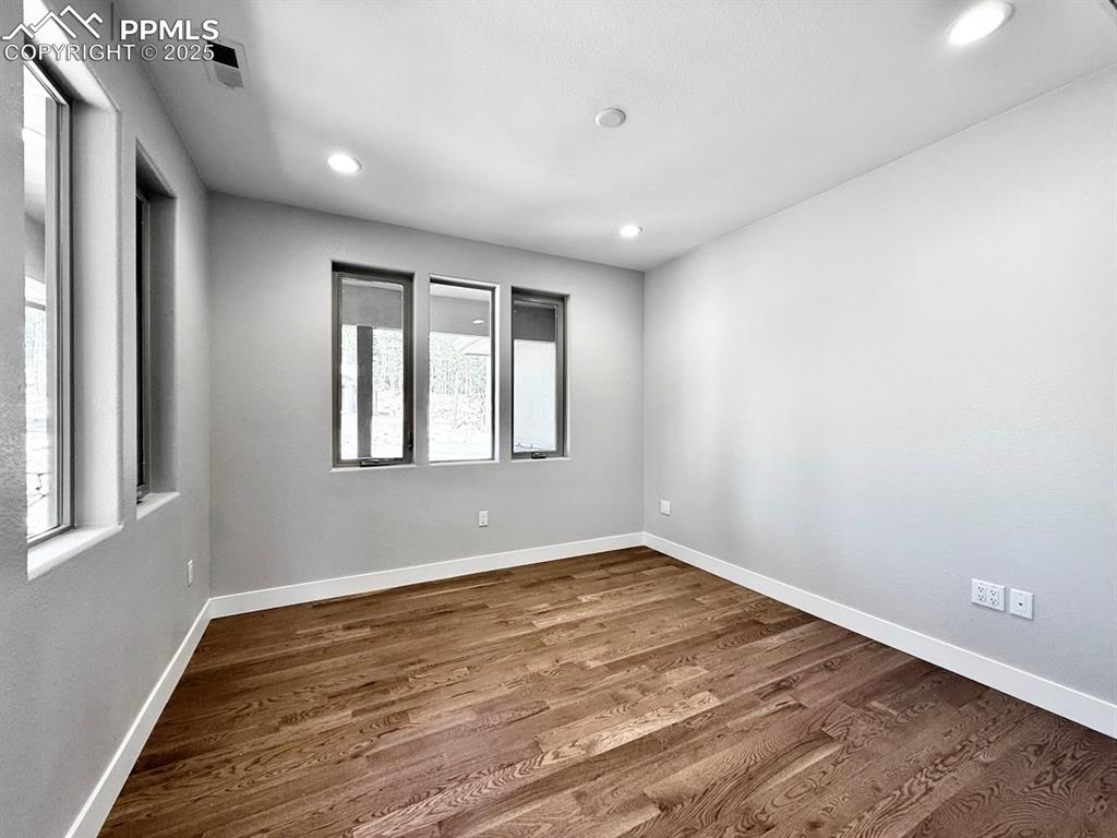 Image 3 of 28: Empty room with dark wood-style floors and recessed lighting