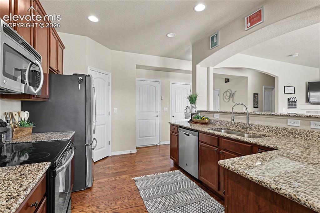 Image 10 of 38: Kitchen featuring wood-finish flooring, granite countertops, and dark wood