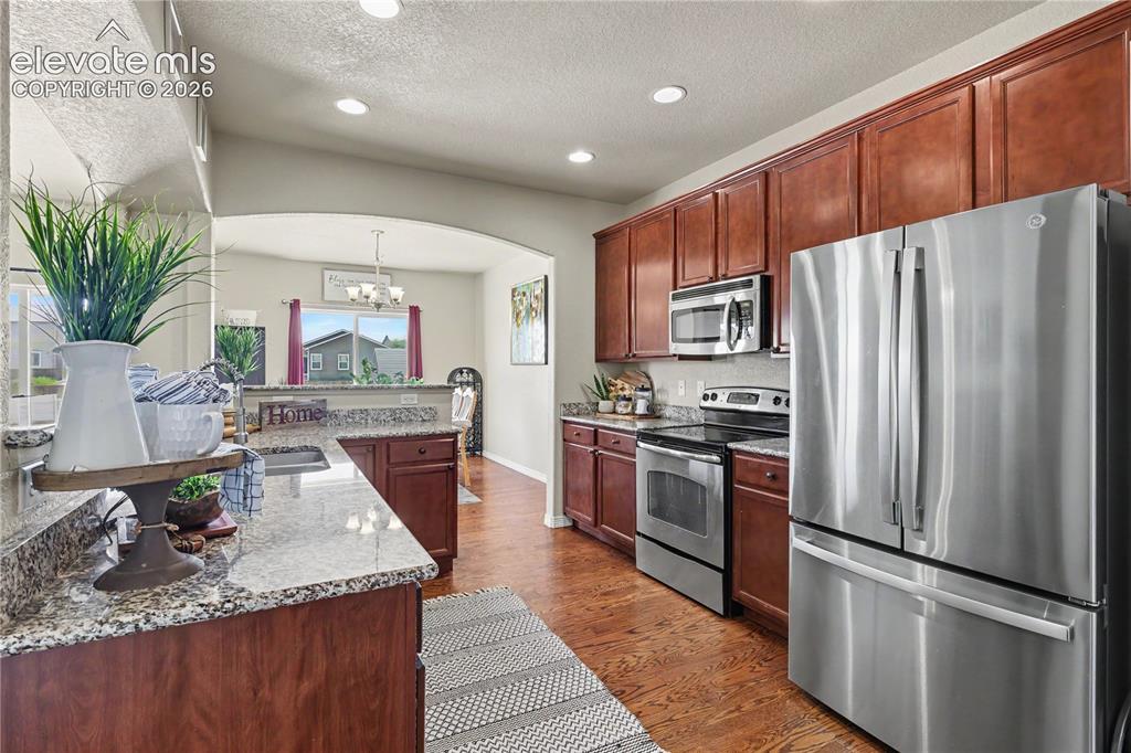 Image 11 of 38: Kitchen featuring wood-finish flooring, recessed lighting, and rich wood ca