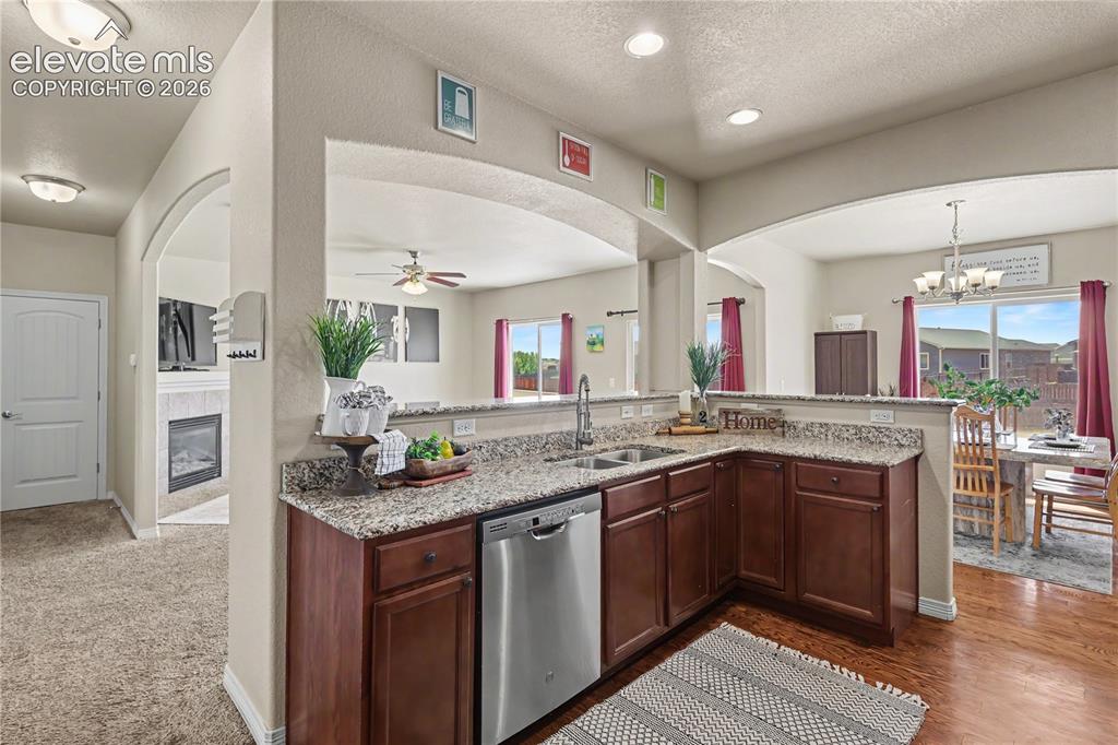 Image 12 of 38: Kitchen featuring granite countertops, wood-finish cabinetry, a double basi