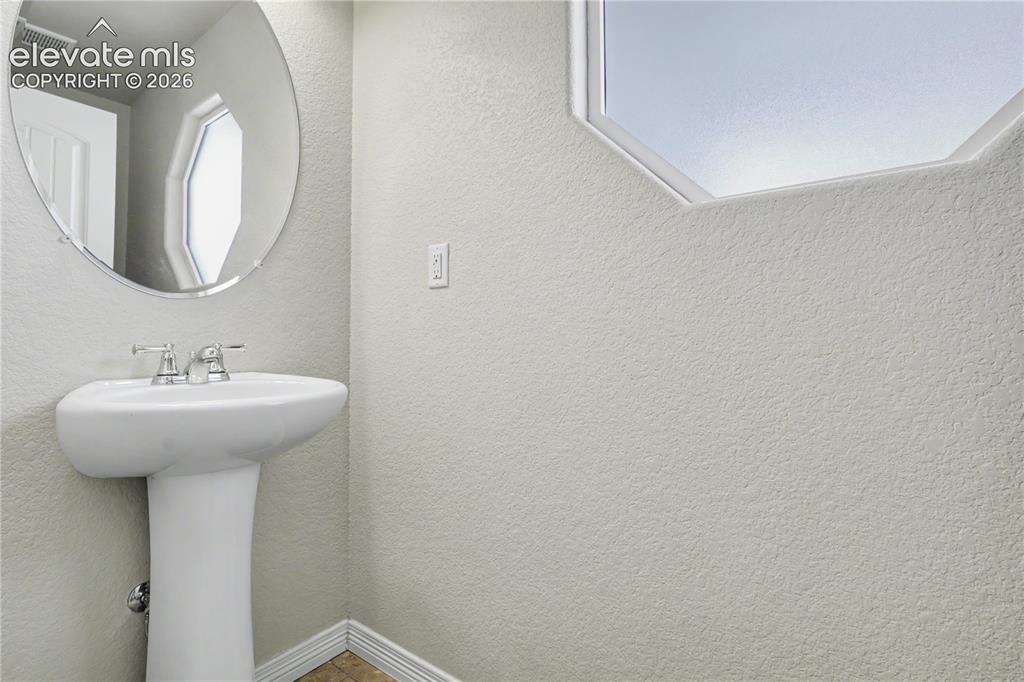 Image 13 of 38: Pedestal sink with chrome fixtures and an oval wall mirror
