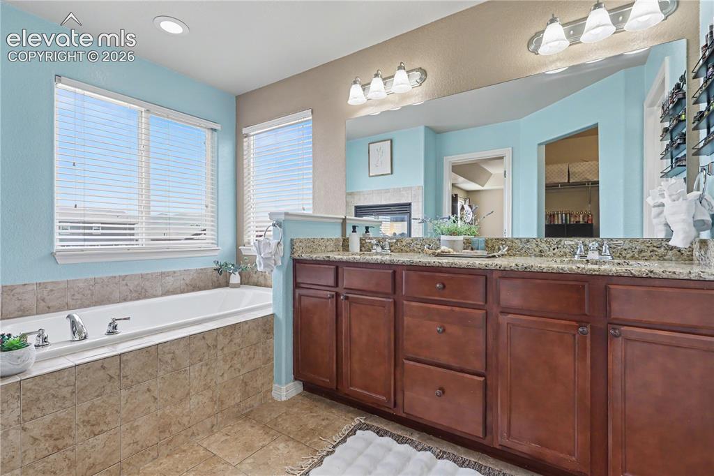 Image 17 of 38: Bathroom featuring a built-in soaking tub with tiled surround, dual windows