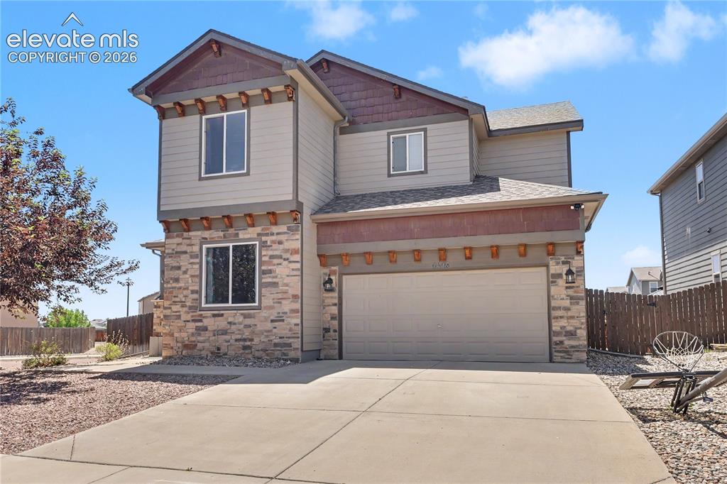 Image 2 of 38: Two-story residence featuring a stone and siding exterior, an attached two-
