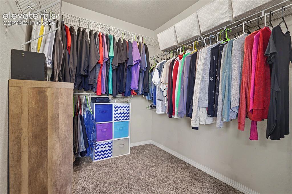 Image 20 of 38: Walk-in closet featuring wall-mounted wire shelving, multiple hanging rods,