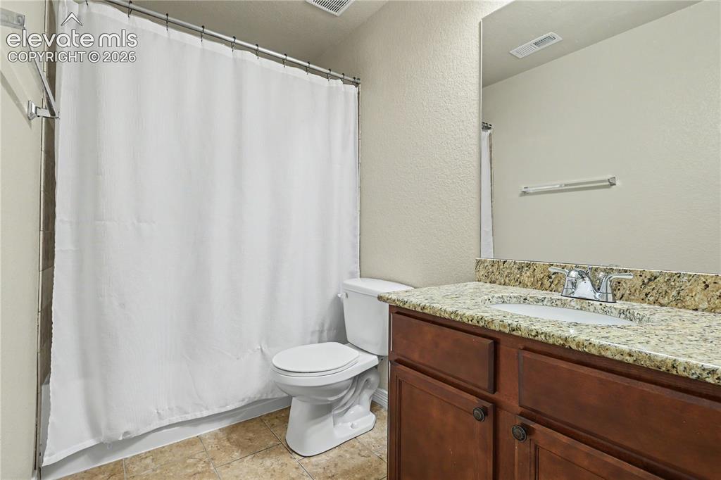 Image 31 of 38: Bathroom featuring a dark wood-finish vanity with a light-toned, speckled c