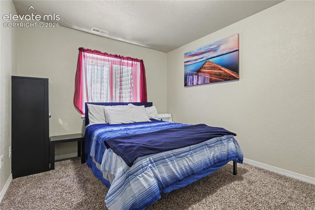 Image 32 of 38: Carpeted bedroom featuring a single window, baseboard trim, and light-toned