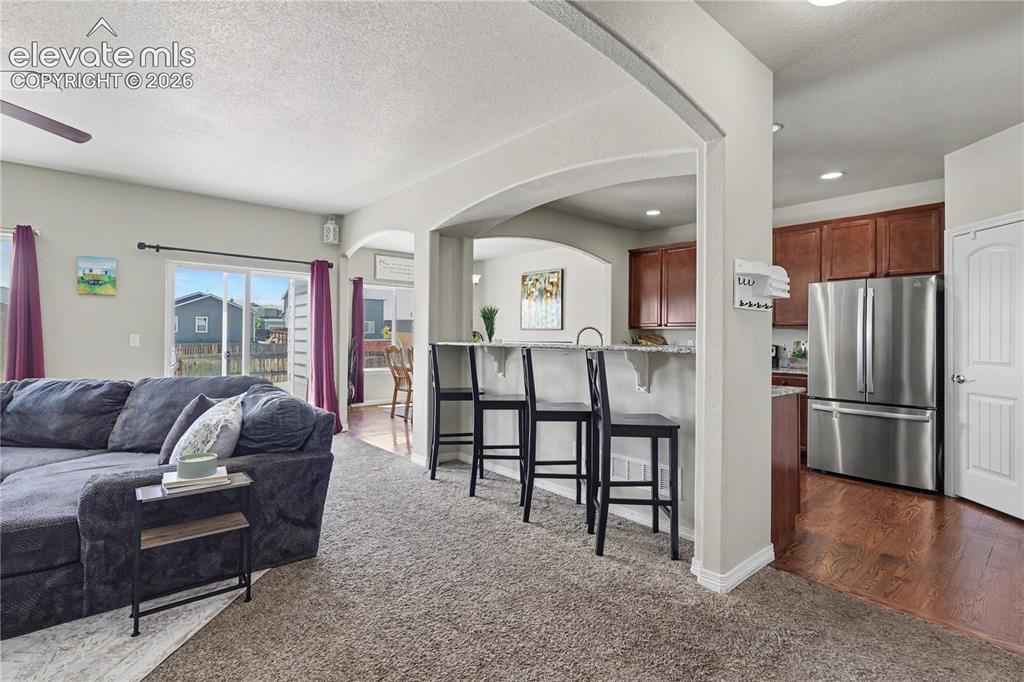 Image 4 of 38: Open-concept living space featuring a carpeted area, arched entryway, and s