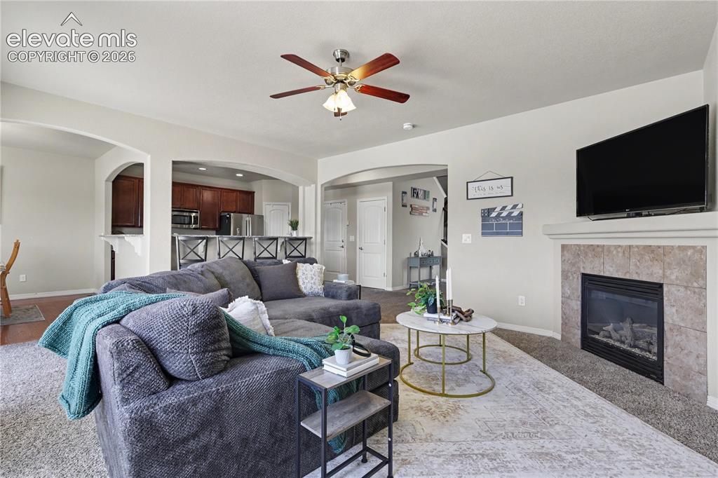 Image 7 of 38: Living area featuring a gas fireplace with a tiled surround and mantel, ove
