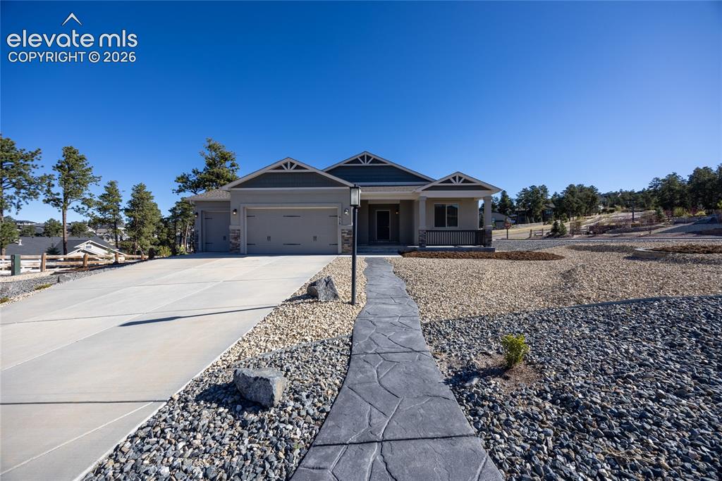 Caption: Contemporary ranch-style home featuring a covered porch with stone columns, a concrete driveway, and