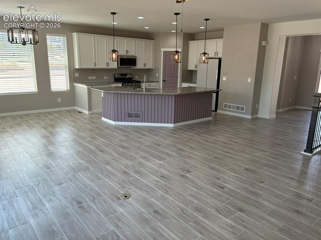 Image 11 of 48: Open concept kitchen featuring an island with a stone-finish countertop, wh