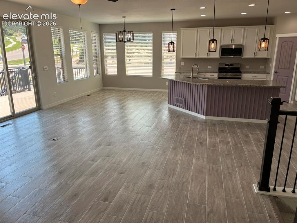 Image 13 of 48: Open-concept living space with wood-finish tile flooring, a kitchen island 