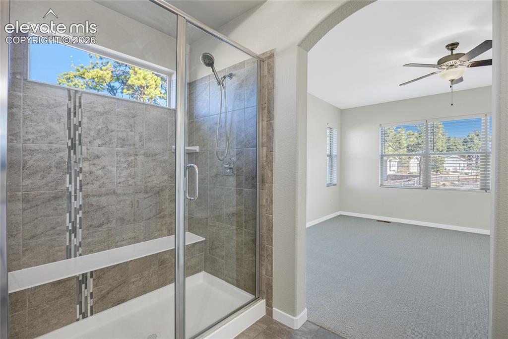 Image 26 of 48: Glass-enclosed shower with tile surround and integrated shelving, transom w