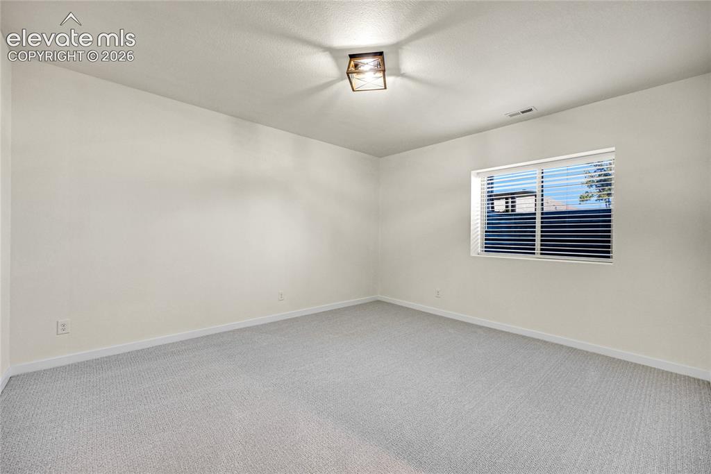 Image 34 of 48: Light-colored walls, patterned carpet, recessed window with horizontal blin