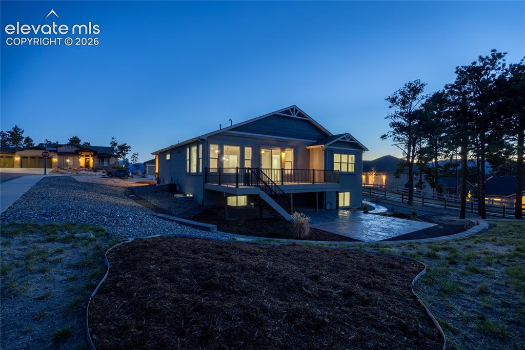 Image 40 of 48: Rear exterior featuring a spacious deck with dark railings, a lower-level p